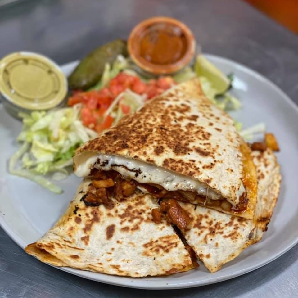 A chicken quesadilla from Catrina's Mexican Food, with melted cheese, lettuce, tomatoes, and sauces.